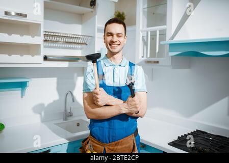 Fröhlicher männlicher Klempner hält Schraubenschlüssel und Kolben Stockfoto