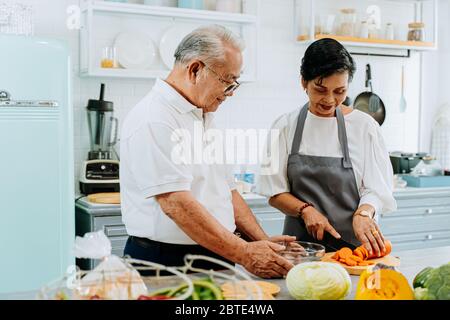 Senior Asian verheiratet paar Kochen Essen in der Küche zu Hause. Ältere 70er Jahre Mann und Frau bereiten Zutaten an der Küchentheke zusammen. Stockfoto