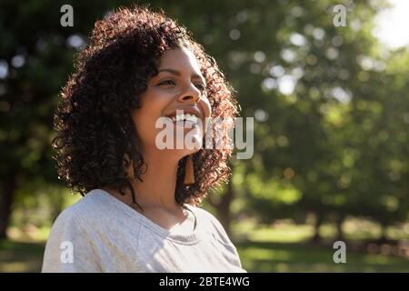 Lächelnde junge Frau genießt einen sonnigen Tag im Park Stockfoto