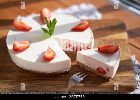 Scheibe Erdbeerkäsekuchen auf weißem Hintergrund, selektiver Fokus, quadratisches Bild. Stockfoto