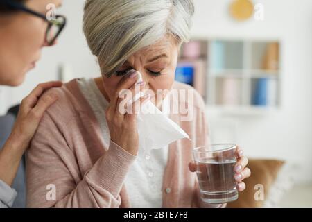Nahaufnahme Porträt von eleganten älteren Frau weinend während der Therapie-Sitzung und hält Glas Wasser mit weiblichen Psychologen trösten sie Stockfoto