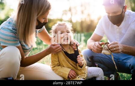 Familie mit wingenden kleinen Tochter auf Reise in der Natur, trägt Gesichtsmasken. Stockfoto