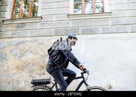 Lieferung Mann Kurier mit Gesichtsmaske und Fahrrad Radfahren in der Stadt. Stockfoto