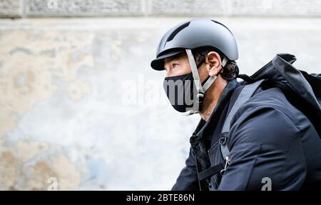 Lieferung Mann Kurier mit Gesichtsmaske und Fahrrad Radfahren in der Stadt. Stockfoto