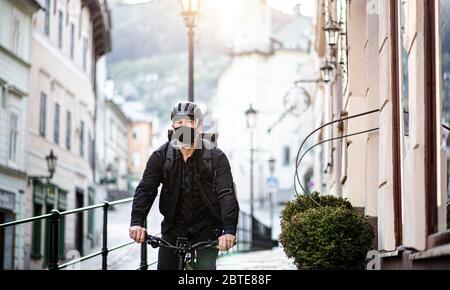 Lieferung Mann Kurier mit Gesichtsmaske und Fahrrad Radfahren in der Stadt. Stockfoto