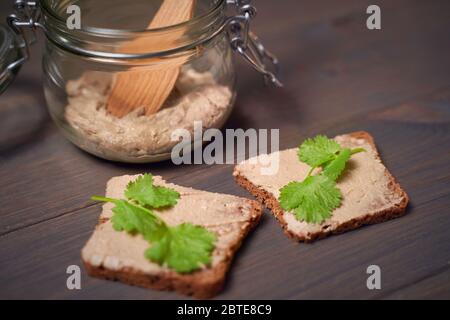 Hausgemachte Fleischpastete auf geröstetem knusprigem Brot. Dunkle Fototil Stockfoto