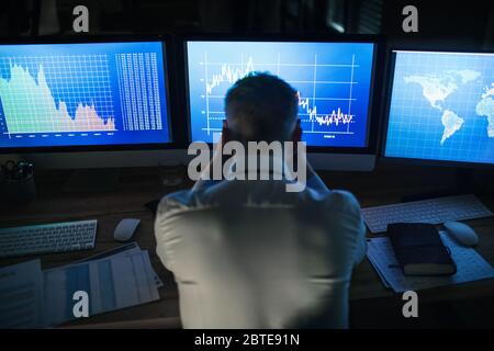 Rückansicht eines frustrierten Geschäftsmannes mit Computer am Schreibtisch. Konzept der Finanzkrise. Stockfoto