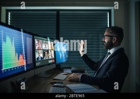 Geschäftsmann mit Computer am Schreibtisch, der spät arbeitet. Konzept für Videoanruf. Stockfoto
