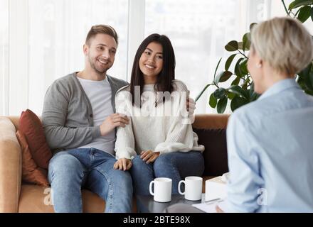 Fröhliches Familienpaar Im Gespräch Mit Berater Sitzen Im Büro Stockfoto