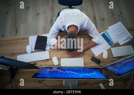 Von oben aus hatte ich einen müden Geschäftsmann mit Computer am Schreibtisch. Konzept der Finanzkrise. Stockfoto