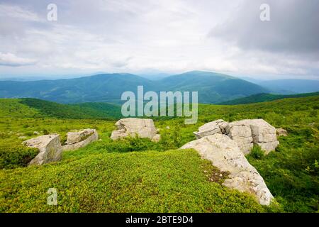 Riesige Steine im Tal auf dem Bergrücken. Bergsommerlandschaft. Wiese mit riesigen Steinen unter dem Gras auf dem Hügel in der Nähe der Erbse Stockfoto