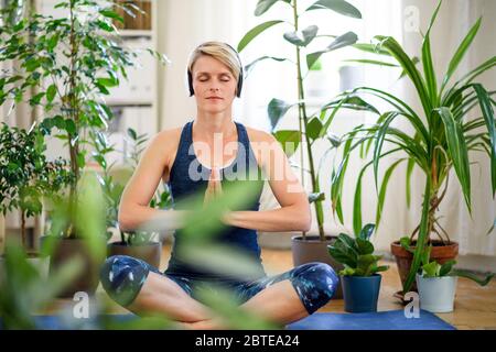 Vorderansicht der jungen Frau drinnen zu Hause, dabei Yoga-Übung. Stockfoto