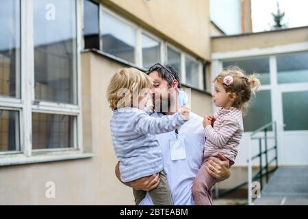 Kinder grüßen Vater Arzt vor dem Krankenhaus, Ende des Coronavirus. Stockfoto