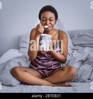 Zerfall Konzept. Weinendes Mädchen, das Eis im Bett isst Stockfoto
