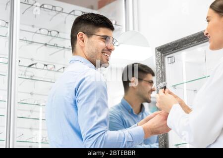 Optometriker hilft jungen Mann, Brille zu wählen Stockfoto