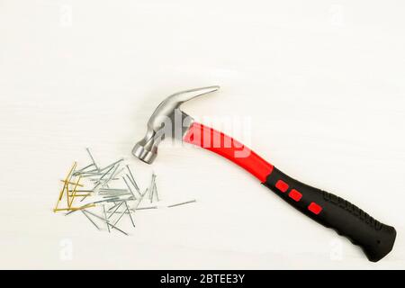 Hammer mit rotem Griff und vielen Nägeln auf weißem Hintergrund, Draufsicht Stockfoto