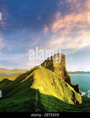 Unglaubliche Sonnenuntergang Landschaft mit kallur Leuchtturm auf grünen Hügeln der Insel Kalsoy, Färöer, Dänemark Stockfoto