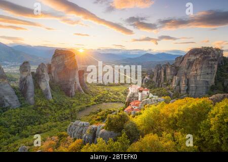 Landschaft von Meteora, Griechenland bei romantischem Sonnenuntergang mit echter Sonne und Sonnenuntergang Himmel. Meteora - unglaubliche Sandsteinfelsen. Die Meteora-Gegend Stockfoto