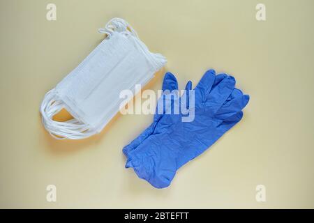 Antivirale chirurgische Ohrbügel-Masken mit 3 Schichten und ein Paar Handschuhe zum Schutz vor Corona-Viren und Bakterien. Medizinische Schutzmasken und Handschuhe o Stockfoto