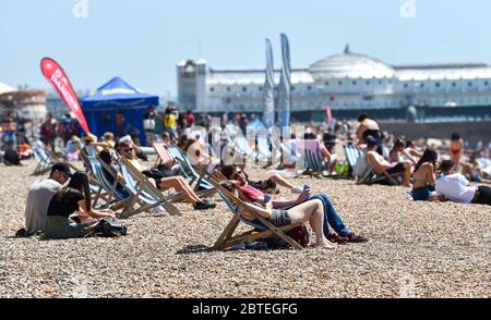Brighton UK 25. Mai 2020 - Besucher genießen den Feiertagshitzigen Sonnenschein am Brighton Strand heute, da die Temperaturen während der Coronavirus COVID-19 Pandemie-Krise die hohen 20er Jahre im Südosten Englands erreichen werden. Quelle: Simon Dack / Alamy Live News Stockfoto