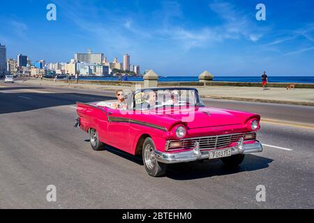 Rotes altes Auto, das entlang der Malecon, Havanna, Kuba fährt Stockfoto