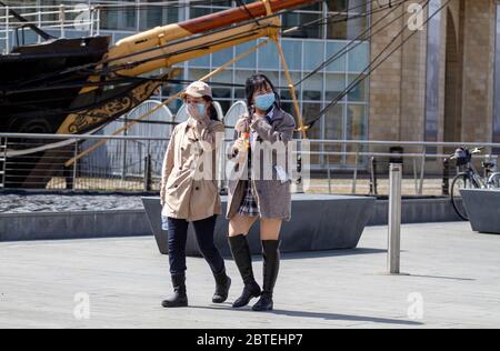 Dundee, Tayside, Schottland, Großbritannien. Mai 2020. UK Wetter: Warmer, trüber Sonnenschein in Nordostschottland mit einer maximalen Temperatur von 21 Grad Zwei chinesische Frauen tragen Schutzmasken und genießen das herrliche heiße Wetter, während sie während der Sperrbeschränkungen von Covid-19 am RRS Discovery-Schiff entlang der Küste in Dundee vorbeilaufen. Quelle: Dundee Photographics/Alamy Live News Stockfoto