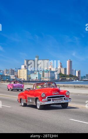 Altes rotes Auto, das entlang der Malecon, Havanna, Kuba fährt Stockfoto