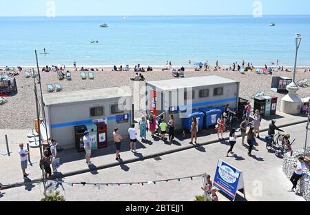 Brighton UK 25. Mai 2020 - Besucher stellen sich für die öffentlichen Toiletten an, während sie den Feiertagshitzigen Sonnenschein am Brighton Strand genießen, da die Temperaturen während der Coronavirus COVID-19 Pandemie-Krise die hohen 20er Jahre im Südosten Englands erreichen werden. Quelle: Simon Dack / Alamy Live News Stockfoto