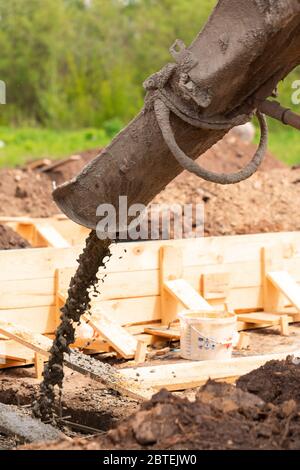 Verlegung des Zements oder Betons in die Fundamentschalung mit automatischer Pumpe. Gebäude Haus Fundament Stockfoto