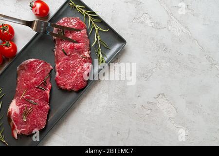 Zwei frische rohe Fleischsteaks auf schwarzer Keramikplatte Stockfoto