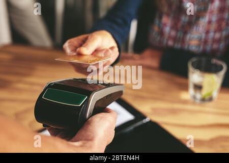 Kunden, die kontaktlos mit Kreditkarte bezahlen. Kassierer mit Kreditkartenleser Maschine akzeptiert Zahlung über nfc-Technologie. Stockfoto