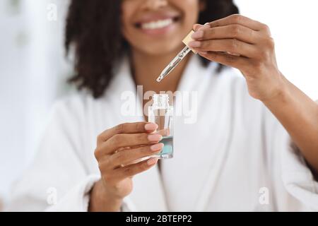 Schönheit Und Hautpflege. Lächelnde Schwarze Frau Holding Flasche Mit Feuchtigkeitsspendende Gesicht Serum Stockfoto