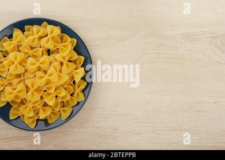 Rohe Pasta in Form eines Bogens auf einem Teller, Draufsicht, freier Platz für Text Stockfoto