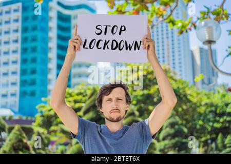 Mann hält ein Poster Stop Lockdown. Handgeschriebener Text - Schriftzug isoliert auf weiß. Coronovirus COVID 19-Konzept Stockfoto