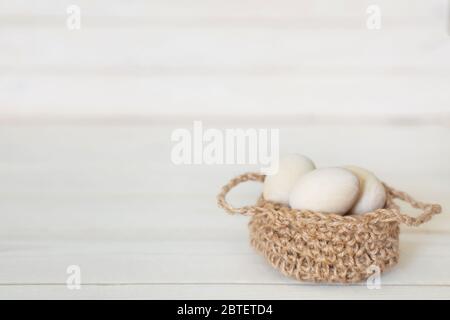 Hölzerne Ostereier in einem Korbgeflecht, gestrickt Korb. Weißer Holzhintergrund. Stockfoto