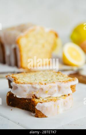 Nahaufnahme von Scheiben glasierten Zitrone Pfund Kuchen Laib mit Mohn und Zitronenschale. Geringe Schärfentiefe Stockfoto