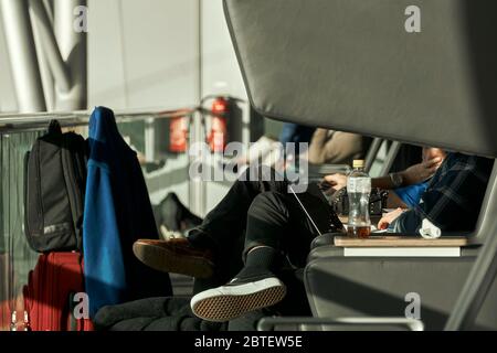 Passagiere des Brüsseler Flughafens warten in der Halle auf den Privatsitzen mit Gepäck und Notebook Stockfoto