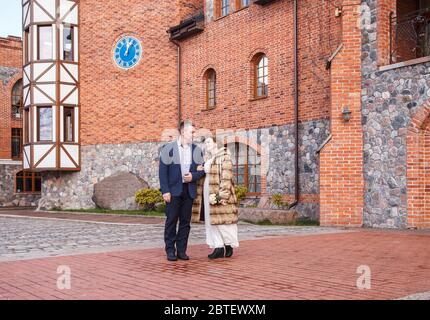 Frisch verheiratetes Paar, das am frühen Frühlingstag in der Nähe des Schlosses im Stadtpark steht Stockfoto