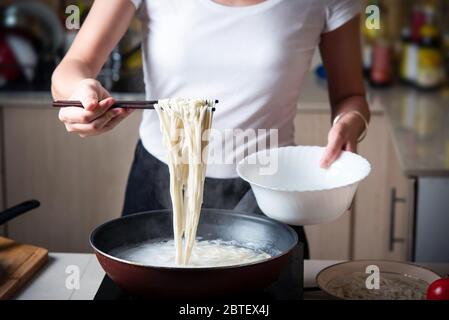 Frau, die Nudeln in der Küche kocht. Zubereitung von Speisen zu Hause Stockfoto