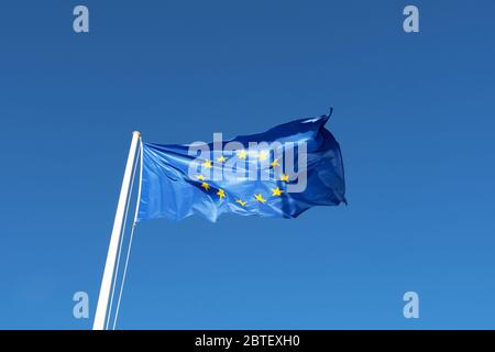 EU-Flagge - blaue Leinwand mit gelben Sternen wehen in blauen klaren Himmel Stockfoto
