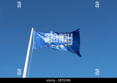 EU-Flagge - blaue Leinwand mit gelben Sternen wehen in blauen klaren Himmel Stockfoto