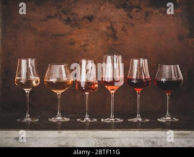 Verschiedene Schattierungen von Roséwein in Gläsern auf braunem Hintergrund Stockfoto
