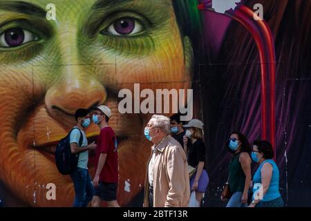 Madrid, Spanien. Mai 2020. Menschen, die Schutzmaske tragen, gehen an einem Wandgemälde in der Gran Via Straße vorbei. Madrid hat die sogenannte Phase-1-Transition von der Sperrung des Coronavirus betreten, die es vielen Geschäften ermöglicht, wieder zu eröffnen, sowie Restaurants, die Kunden im Freien bedienen. Quelle: Marcos del Mazo/Alamy Live News Stockfoto