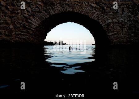 Europa, Portugal, Caiscas. Ein Mann schwimmt mitten auf der Brücke, die den Palácio dos Condes de Castro Guimarães in Caiscas begrenzt. Stockfoto