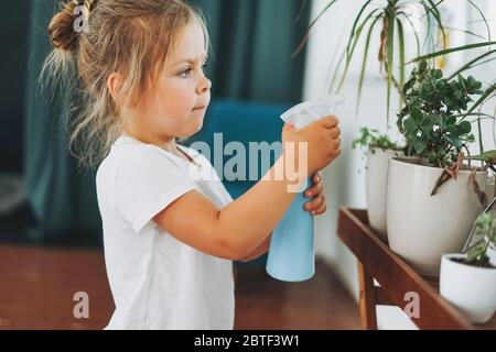 Lustige niedliche Kleinkind Mädchen Bewässerung Haus Pflanze auf Zimmer in Hause Stockfoto