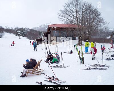 GREVENA, GRIECHENLAND - 24. MÄRZ 2018: Skigebiet Vasilitsa mit Schnee und Menschen auf der Piste bei bewölktem Wetter Stockfoto