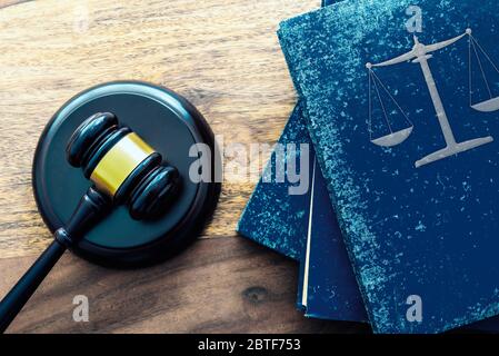 Die Draufsicht des Richters gavel und den Stapel der alten Gesetzbücher mit den Maßstäben der Gerechtigkeit auf dem hölzernen Tisch Stockfoto