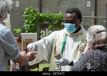 Italien - 2020. Mai 24: Der Priester feiert die Messe während der Blockade des Covid-19. Die Gläubigen empfangen die Heilige Hostie mit Handschuhen und Schutzmasken. Stockfoto