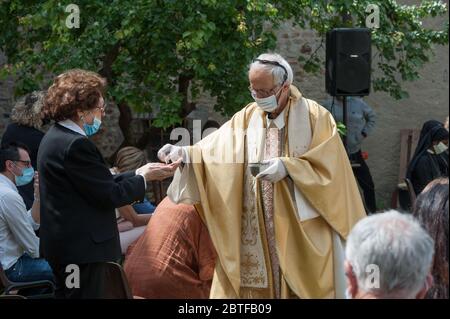 Italien - 2020. Mai 24: Der Priester feiert die Messe während der Blockade des Covid-19. Die Gläubigen empfangen die Heilige Hostie mit Handschuhen und Schutzmasken. Stockfoto