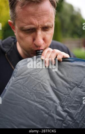 Nahaufnahme von Mann bläst ein selbst aufblasbare Schlafpolster für Camping Stockfoto